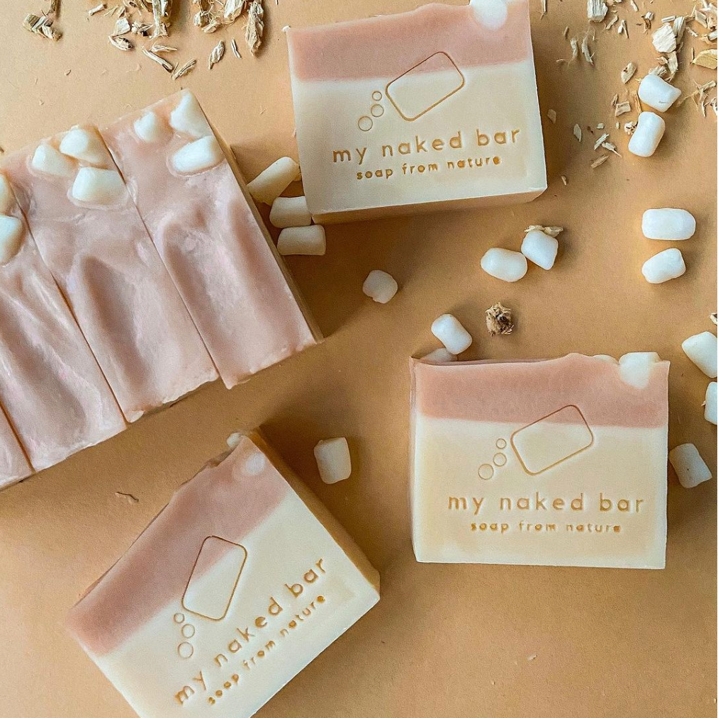 My Naked Bar Marshmallow Bubblegum soap bars on a beige background with marshmallow soap dough and marshmallow root sprinkled around